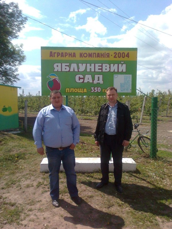 Олександр Фоменко (ліворуч), Роман Яковенко (праворуч) на фоні яблуневого саду ВАТ "Аграрна компанія 2014"